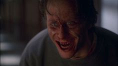 a creepy man with blue eyes looking at something in the distance while wearing a gray shirt