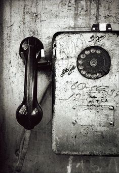 an old fashioned phone is attached to a wall with graffiti on it and has two dials