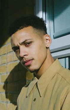 a young man standing in front of a brick wall