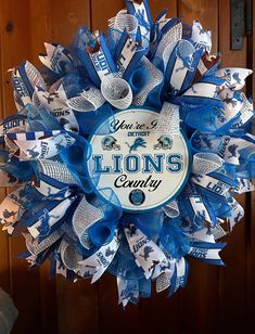 a detroit lions wreath hanging on a door with blue and white ribbon around the edges