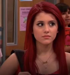 a woman with long red hair is looking at the camera