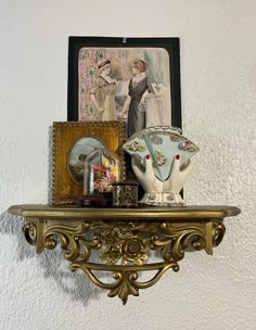 an ornate shelf with two vases and pictures on it