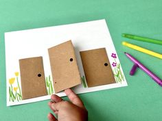 someone is holding up two cardboard houses made to look like they are standing in the grass