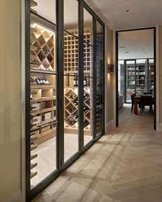 a wine cellar in the middle of a room with glass doors leading to another room