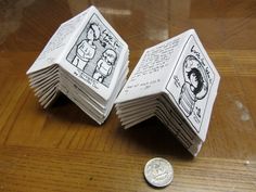 two origami books sitting on top of a wooden table next to a penny