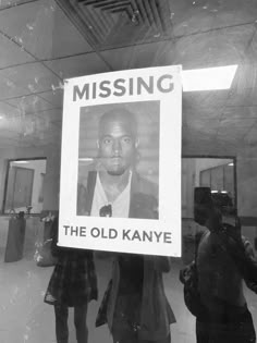 a black and white photo of a man holding a missing poster in front of a mirror