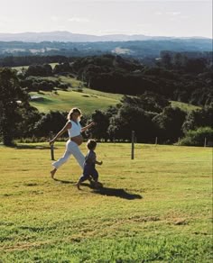 a woman holding a baseball bat while standing next to a little boy on a field
