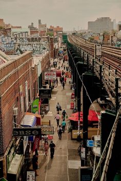people are walking down the street near train tracks