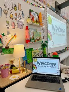 an open laptop computer sitting on top of a white desk in front of a large screen