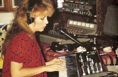 a woman with headphones on playing an electronic keyboard in front of a recording equipment