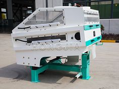 a large white machine sitting on top of a cement floor in front of a building