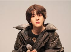 a young man in black leather jacket holding a microphone