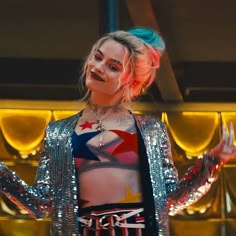 a woman with pink hair and tattoos on her chest standing in front of a stage