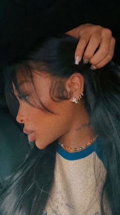 a woman with long black hair and piercings on her ear is sitting in the back seat of a car