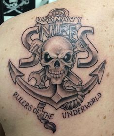 a skull and anchor tattoo on the back of a man's shoulder