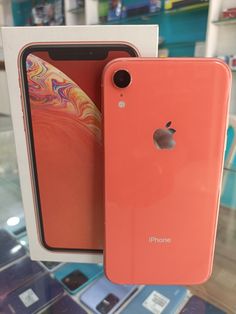 an orange iphone is sitting in a box next to it's packaging on display
