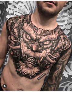 a man with tattoos on his chest and chest is looking at the camera while wearing a dragon