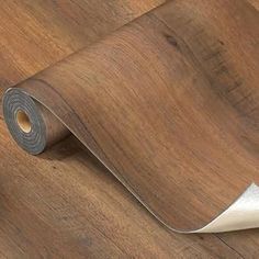a roll of wood flooring next to a wall with a white tape on it