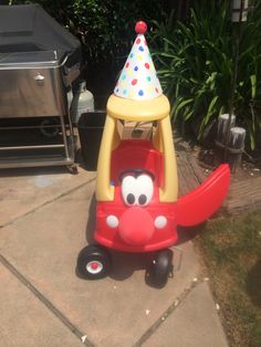 a toy airplane with a birthday hat on it's head sitting in the driveway