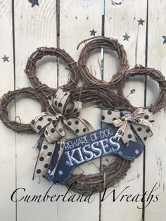 a wreath with polka dots and ribbons hanging on the side of a wooden fence that says, make god kisses