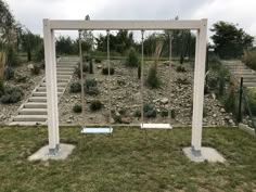 two white benches sitting on top of a lush green field next to a stone wall