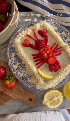 there is a cake decorated with strawberries and lemons on the plate next to it