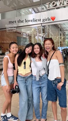 four girls standing together in front of a building
