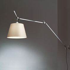 a lamp that is on top of a table next to a wall with a light on it