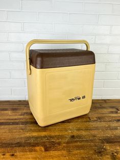 a yellow and brown cooler sitting on top of a wooden table next to a brick wall