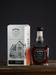 a bottle of jack daniels christmas edition sitting next to a box on a wooden table