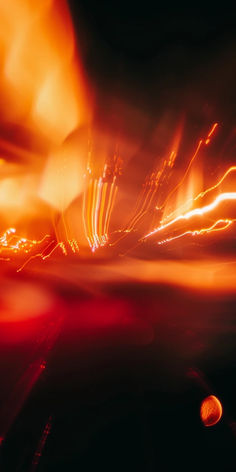 blurry photograph of street lights in the night with orange and red light from cars