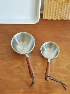 two spoons sitting on top of a wooden table