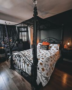 a bedroom with a canopy bed and halloween decorations on the walls, hardwood flooring
