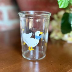 a glass with a duck on it sitting on a table