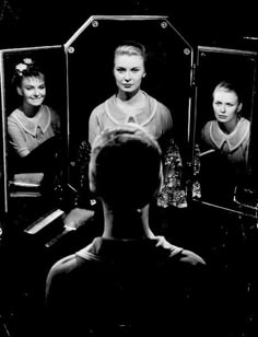 a woman standing in front of a mirror with three mirrors behind her and the reflection of another person's face
