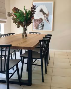 a dining room table with chairs and a vase filled with flowers on top of it