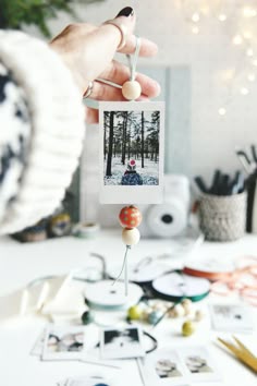 a person holding an object in front of a table with pictures and other items on it