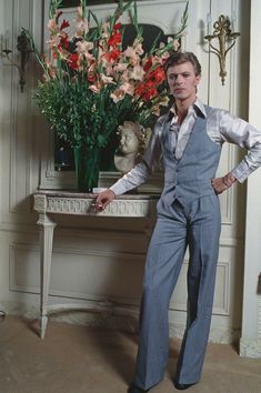 a man standing in front of a vase with flowers on it and his hands on his hips