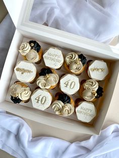 a box filled with lots of cupcakes on top of a white table cloth