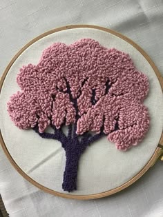 a pink and purple tree is on a white wall hanging in front of a wooden hoop
