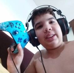 a shirtless boy wearing headphones and holding a controller