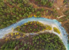 an aerial view of a river in the middle of some trees and land with blue water