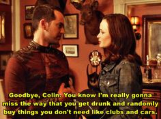 a man and woman standing next to each other in a room with pictures on the wall