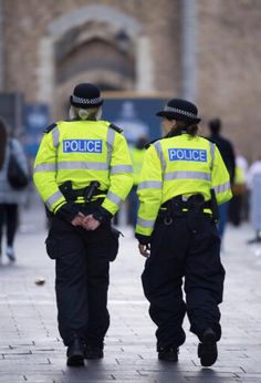 two police officers are walking down the street