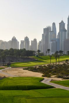 a golf course in the foreground with city skyline in the background