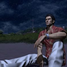 a man sitting on the ground in front of a body of water at night time