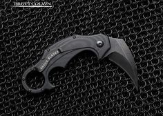 a knife that is laying on some kind of black chain link material with the words, breitt colvin