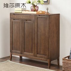 a wooden cabinet sitting on top of a hard wood floor next to a vase with flowers