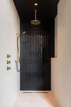 a black and white tiled shower with gold faucet in the corner next to it
