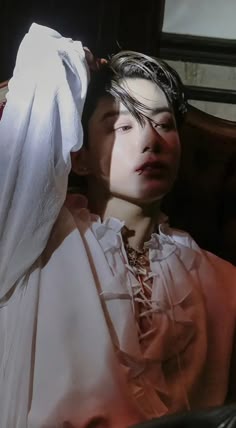 a woman in a white dress sitting on a chair with her head covered by a veil